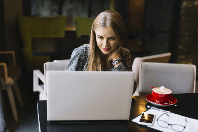 Mujer diseñando sitio web de restaurante en ordenador en cafetería