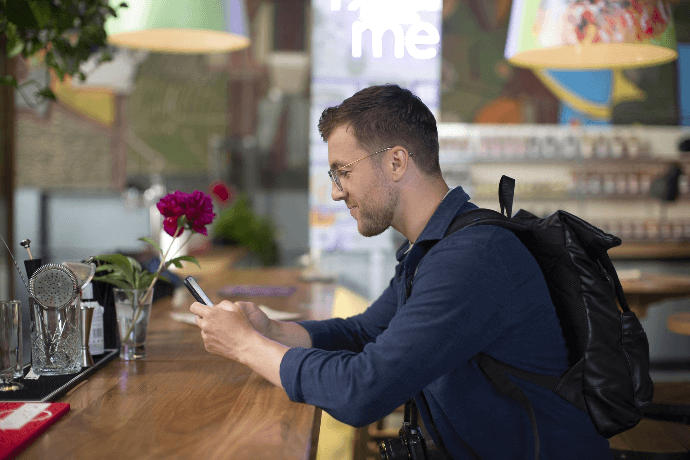 Hombre reservando habitación de hotel con smartphone en la barra