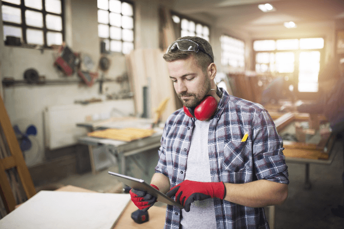 Carpintero autónomo gestionando pedidos desde tablet en taller