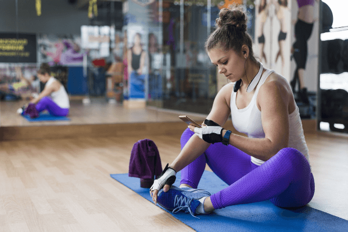 Mujer en gimnasio utilizando smartphone para ejercicios y planificación