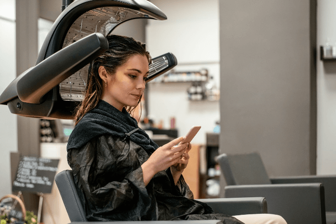 Cliente relajándose bajo secador de cabello en salón de belleza