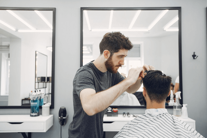 Estilista cortando el cabello a cliente en peluquería moderna