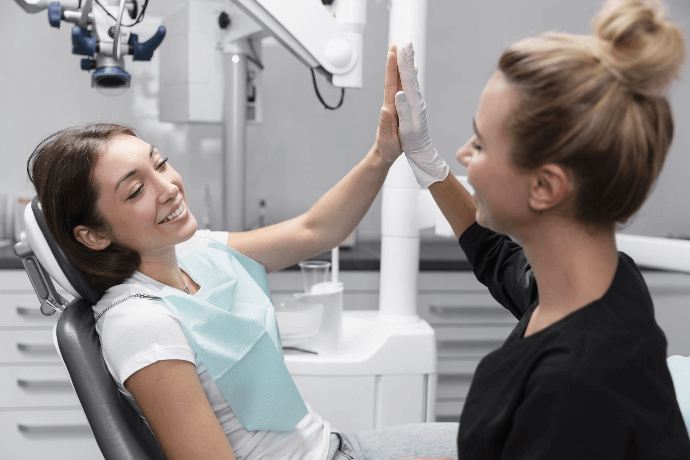 Paciente feliz dando un 'high-five' a dentista tras consulta exitosa